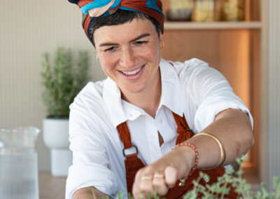 food creator al lavoro tra erbe aromatiche, parte del servizio fotografico di Elisa Fedrizzi in cucina luminosa.