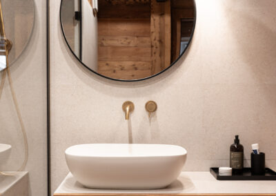 Dettaglio bagno con specchio rotondo e finiture in legno naturale, fotografia d’interni