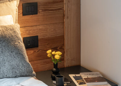 Camera da letto in legno con luce soffusa e dettagli curati, fotografia d’interni alpini di Elisa Fedrizzi