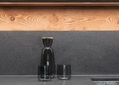 Dettaglio cucina con bicchieri colorati e materiali naturali, fotografia d’interni alpini