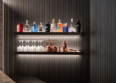 Dettaglio bar dell’Hotel Paganella, bottiglie illuminate e texture nera.