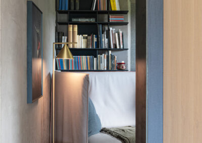 Zona lettura accogliente, fotografia d’interni calda e raffinata.