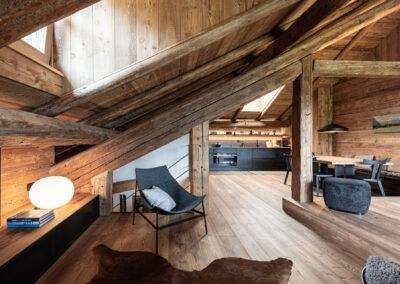 Open space nel sottotetto con travi in legno e arredamento alpino contemporaneo, fotografia d’interni