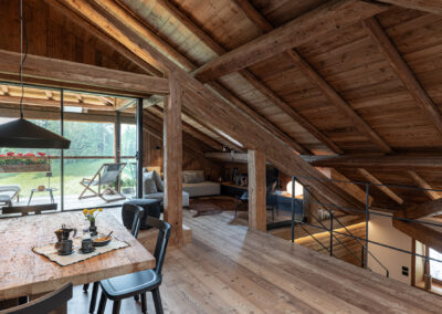Soggiorno in legno con travi a vista e grandi finestre, fotografia d’interni alpini di Elisa Fedrizzi