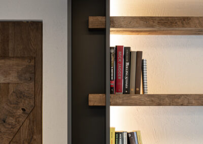Dettaglio libreria su misura con illuminazione integrata in progetto di interior design alpino contemporaneo.